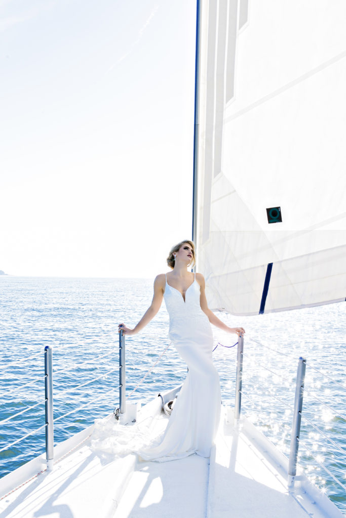 bride standing on bow of sailboat in a wedding dress